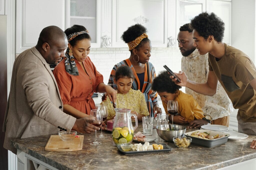 A joyful family gathering in the kitchen, enjoying food and drinks together.